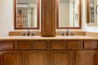 Bathroom - mid-sized traditional master beige tile and ceramic tile travertine floor and beige floor bathroom idea in Denver with raised-panel cabinets, dark wood cabinets, beige walls, an undermount sink, granite countertops and a hinged shower door