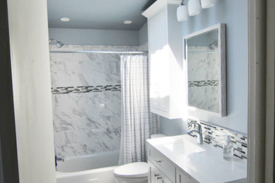 This is an example of a medium sized traditional ensuite bathroom in Baltimore with recessed-panel cabinets, white cabinets, an alcove bath, a shower/bath combination, a two-piece toilet, black and white tiles, ceramic tiles, blue walls, ceramic flooring, a submerged sink, granite worktops, grey floors, a shower curtain, white worktops, double sinks, a built in vanity unit and a vaulted ceiling.