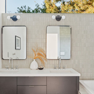 Drop-in bathtub - contemporary master gray tile brown floor drop-in bathtub idea in Los Angeles with flat-panel cabinets, gray cabinets, white walls, an undermount sink and white countertops