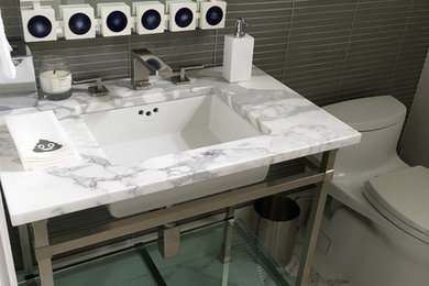 Diseño de cuarto de baño contemporáneo de tamaño medio con sanitario de una pieza, baldosas y/o azulejos grises, baldosas y/o azulejos de vidrio, paredes grises, suelo con mosaicos de baldosas, aseo y ducha, lavabo bajoencimera, encimera de mármol y suelo gris