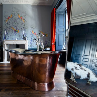 Foto de cuarto de baño bohemio con bañera exenta, paredes azules, suelo de madera oscura y suelo marrón
