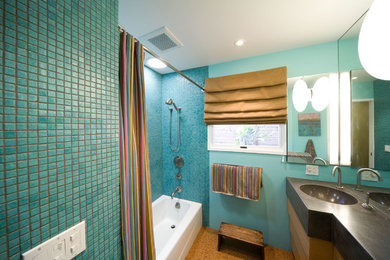 サンルイスオビスポにある中くらいなコンテンポラリースタイルのおしゃれなバスルーム (浴槽なし) (コンクリートの洗面台、シャワーカーテン、フラットパネル扉のキャビネット、中間色木目調キャビネット、アルコーブ型浴槽、シャワー付き浴槽	、青いタイル、モザイクタイル、青い壁、コルクフローリング、一体型シンク、茶色い床、グレーの洗面カウンター) の写真