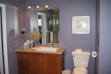 Modelo de cuarto de baño tradicional con armarios estilo shaker, puertas de armario de madera oscura, bañera encastrada, paredes púrpuras, lavabo encastrado y encimera de granito