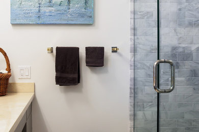 Example of a trendy gray tile and stone tile porcelain tile alcove shower design in Minneapolis with flat-panel cabinets, gray cabinets, marble countertops and white walls