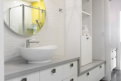 Пример оригинального дизайна: детская ванная комната среднего размера в современном стиле с плоскими фасадами, белыми фасадами, угловым душем, белой плиткой, керамической плиткой, белыми стенами, полом из керамической плитки, настольной раковиной, столешницей из ламината и серым полом