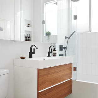 Retro Badezimmer mit flächenbündigen Schrankfronten, hellbraunen Holzschränken, Badewanne in Nische, Duschbadewanne, weißen Fliesen, Waschtischkonsole, grünem Boden, offener Dusche, Doppelwaschbecken und schwebendem Waschtisch in San Francisco
