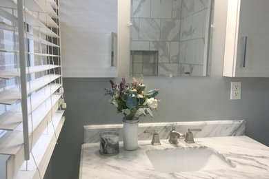 Imagen de cuarto de baño actual de tamaño medio con armarios estilo shaker, puertas de armario blancas, paredes grises, aseo y ducha y lavabo bajoencimera