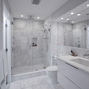 Foto di una piccola stanza da bagno padronale minimalista con ante lisce, ante bianche, doccia alcova, WC monopezzo, piastrelle bianche, piastrelle di marmo, pareti bianche, pavimento in marmo, lavabo sottopiano, top in quarzo composito, pavimento bianco, porta doccia a battente e top bianco