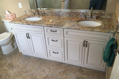 Example of a mid-sized classic master beige tile and ceramic tile travertine floor bathroom design in Newark with raised-panel cabinets, white cabinets, a two-piece toilet, beige walls, an undermount sink and granite countertops
