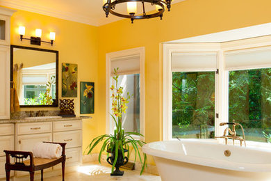 他の地域にある巨大なトラディショナルスタイルのおしゃれなマスターバスルーム (アンダーカウンター洗面器、落し込みパネル扉のキャビネット、白いキャビネット、御影石の洗面台、置き型浴槽、白いタイル、黄色い壁) の写真