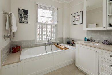 Klassisches Badezimmer mit Einbaubadewanne, blauen Fliesen, Metrofliesen, Kalkstein und beiger Waschtischplatte in London