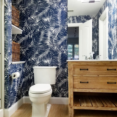 Inspiration for a tropical 3/4 medium tone wood floor and brown floor alcove shower remodel in Philadelphia with flat-panel cabinets, medium tone wood cabinets, a two-piece toilet, multicolored walls, an undermount sink and white countertops