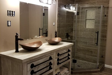 Example of a mid-sized mountain style 3/4 brown tile and porcelain tile porcelain tile and brown floor corner shower design in Baltimore with distressed cabinets, beige walls, a vessel sink, wood countertops, a hinged shower door and gray countertops