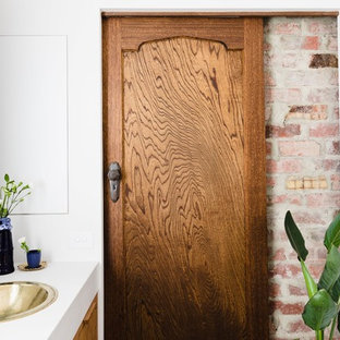 Inspiration for a mediterranean bathroom in Melbourne with flat-panel cabinets, medium wood cabinets, white walls, a drop-in sink and white benchtops.