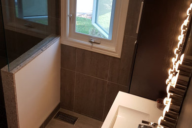 Inspiration for a mid-sized coastal master gray tile and porcelain tile porcelain tile and gray floor corner shower remodel in Toronto with flat-panel cabinets, black cabinets, a one-piece toilet, white walls, an integrated sink, terrazzo countertops, a hinged shower door and white countertops