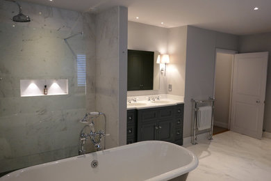 Inspiration for a large traditional ensuite bathroom in Other with recessed-panel cabinets, grey cabinets, a freestanding bath, a built-in shower, a two-piece toilet, white tiles, marble tiles, grey walls, marble flooring, a submerged sink and marble worktops.