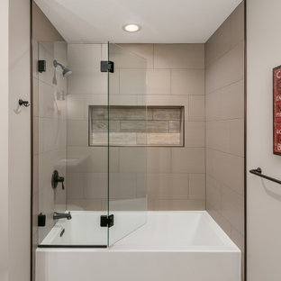 Photo of a mid-sized beach style master bathroom in Minneapolis with flat-panel cabinets, grey cabinets, a drop-in tub, a shower/bathtub combo, a one-piece toilet, beige tile, ceramic tile, beige walls, laminate floors, a drop-in sink, marble benchtops, beige floor, a hinged shower door, multi-coloured benchtops, a single vanity and a floating vanity.
