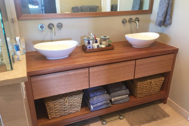 Example of a mid-sized mountain style 3/4 bathroom design in Other with flat-panel cabinets, medium tone wood cabinets, a vessel sink, wood countertops, a two-piece toilet and beige walls
