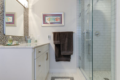 Small transitional master white tile and stone tile marble floor alcove shower photo in Toronto with shaker cabinets, white cabinets, a one-piece toilet, multicolored walls, an undermount sink, marble countertops and a hinged shower door