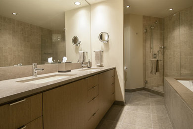 Large trendy master gray tile and stone slab limestone floor and gray floor bathroom photo in Seattle with an undermount sink, flat-panel cabinets, medium tone wood cabinets, a bidet, white walls, solid surface countertops and a hinged shower door