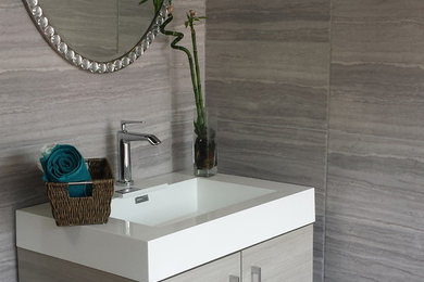 Diseño de cuarto de baño minimalista pequeño con lavabo integrado, armarios con paneles lisos, puertas de armario grises, encimera de acrílico, baldosas y/o azulejos grises, baldosas y/o azulejos de porcelana, paredes grises, suelo de mármol, aseo y ducha y suelo gris