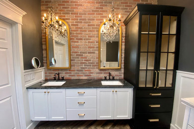 This is an example of a medium sized ensuite bathroom in Cincinnati with white cabinets, a built-in shower, a one-piece toilet, white tiles, porcelain tiles, grey walls, porcelain flooring, a submerged sink, granite worktops, brown floors, an open shower, black worktops, a shower bench, double sinks, a floating vanity unit, a vaulted ceiling and wainscoting.
