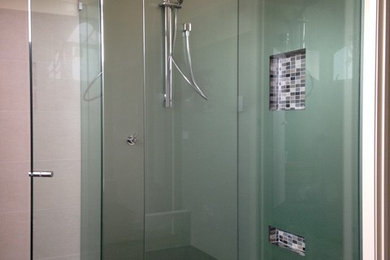 Imagen de cuarto de baño contemporáneo con ducha esquinera, baldosas y/o azulejos de vidrio laminado y suelo de baldosas de porcelana