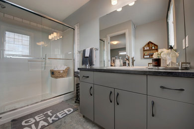 Bathroom - mid-sized transitional master yellow tile and ceramic tile vinyl floor and gray floor bathroom idea in Edmonton with flat-panel cabinets, gray cabinets, a one-piece toilet, gray walls, a drop-in sink, laminate countertops and black countertops