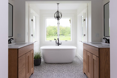 Foto di una stanza da bagno padronale country di medie dimensioni con ante lisce, ante in legno chiaro, vasca freestanding, doccia ad angolo, pareti bianche, pavimento con piastrelle a mosaico, lavabo da incasso, top in quarzite, pavimento multicolore, porta doccia a battente e top bianco