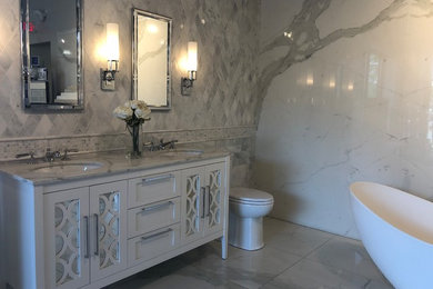 Freestanding bathtub - mid-sized transitional master gray tile and stone slab marble floor and gray floor freestanding bathtub idea in Bridgeport with glass-front cabinets, white cabinets, a two-piece toilet, white walls, an undermount sink, quartz countertops and white countertops