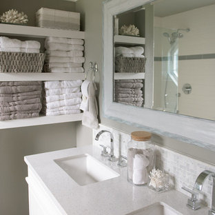 Bild på ett mellanstort maritimt en-suite badrum, med luckor med profilerade fronter, vita skåp, en dusch i en alkov, en toalettstol med separat cisternkåpa, beige kakel, keramikplattor, beige väggar, klinkergolv i porslin, ett undermonterad handfat, marmorbänkskiva, grått golv och dusch med gångjärnsdörr