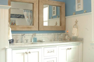 Foto de cuarto de baño costero de tamaño medio con armarios estilo shaker, puertas de armario blancas, sanitario de una pieza, paredes azules, suelo de baldosas de porcelana, aseo y ducha y encimera de mármol