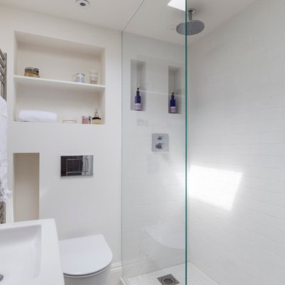 Doorless shower - small transitional master white tile ceramic tile doorless shower idea in London with open cabinets, white cabinets, a wall-mount toilet, white walls and a wall-mount sink