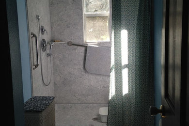 Example of a small country gray tile and porcelain tile pebble tile floor alcove shower design in Orlando with raised-panel cabinets, white cabinets, a two-piece toilet, blue walls, an integrated sink and marble countertops