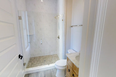 Modelo de cuarto de baño de estilo de casa de campo con armarios estilo shaker, puertas de armario de madera clara, ducha empotrada, baldosas y/o azulejos blancos, encimera de cuarzo compacto y encimeras blancas