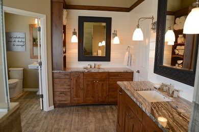 Photo of an expansive rural ensuite bathroom in Portland with shaker cabinets, distressed cabinets, a corner bath, a double shower, a two-piece toilet, brown tiles, porcelain tiles, beige walls, porcelain flooring, a submerged sink and granite worktops.
