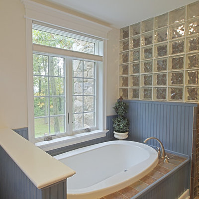 Inspiration for a mid-sized craftsman slate floor drop-in bathtub remodel in Philadelphia with shaker cabinets, blue cabinets, white walls, an undermount sink and solid surface countertops