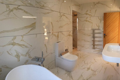 Large modern ensuite bathroom in Other with a freestanding bath, an alcove shower, a two-piece toilet, beige tiles, porcelain tiles, porcelain flooring and a console sink.