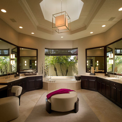 Example of a trendy beige tile beige floor drop-in bathtub design in Miami with an undermount sink, raised-panel cabinets and dark wood cabinets