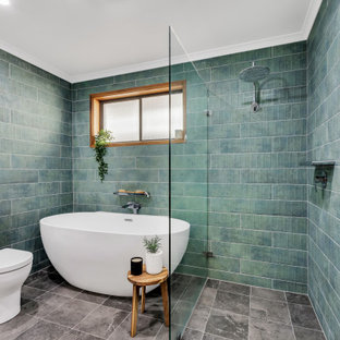 This is an example of a tropical bathroom in Adelaide with dark wood cabinets, a freestanding tub, a curbless shower, blue tile, green tile, grey floor, an open shower and white benchtops.