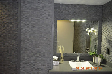 Idées déco pour une salle de bain moderne avec un plan de toilette en surface solide, un carrelage gris, mosaïque, un mur gris et un sol en carrelage de porcelaine.