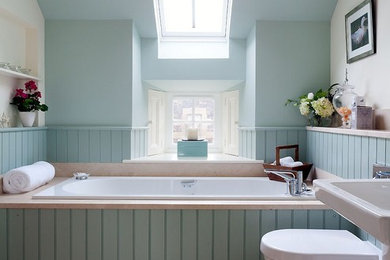 Inspiration for a classic bathroom in Other with a wall-mounted sink, a built-in bath, a wall mounted toilet, blue walls, stone tiles, limestone flooring and beige floors.