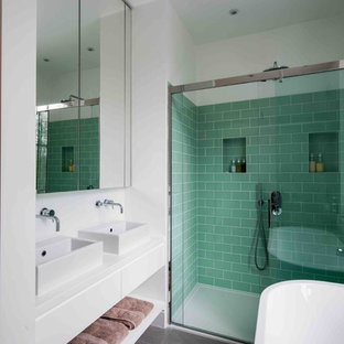 Medium sized contemporary bathroom in London with a freestanding bath, a walk-in shower, green tiles, metro tiles, white walls, a vessel sink, black floors and a sliding door.
