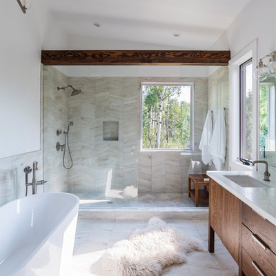 Example of a mountain style beige tile beige floor bathroom design in Denver with flat-panel cabinets, dark wood cabinets, white walls, an undermount sink and white countertops