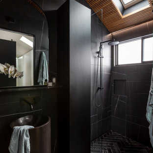 This is an example of a mid-sized contemporary 3/4 bathroom in Sydney with black cabinets, an open shower, black tile, black walls, an integrated sink, black floor, black benchtops, a niche, a single vanity and a freestanding vanity.