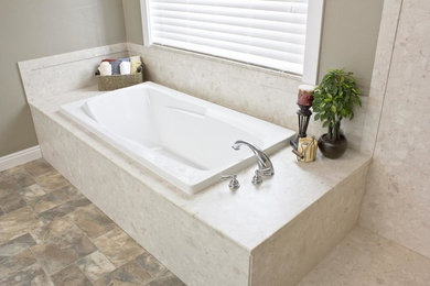 Réalisation d'une grande salle de bain principale tradition avec une baignoire posée, un carrelage beige, un mur beige, un sol en ardoise, des dalles de pierre, un plan de toilette en marbre et un sol marron.