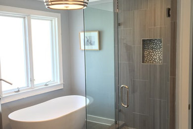 Ejemplo de cuarto de baño actual con bañera exenta, baldosas y/o azulejos grises y suelo de baldosas de porcelana