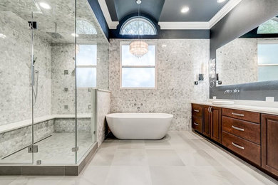 Example of a large trendy master gray tile and marble tile ceramic tile and gray floor bathroom design in Dallas with raised-panel cabinets, dark wood cabinets, a two-piece toilet, gray walls, a vessel sink, solid surface countertops and a hinged shower door