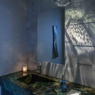 Cette image montre une petit salle d'eau design avec un placard à porte plane, des portes de placard grises, un carrelage blanc, des carreaux de porcelaine, un mur beige, un sol en carrelage de porcelaine, un lavabo intégré, un plan de toilette en granite, un sol gris, un plan de toilette vert et un WC à poser.