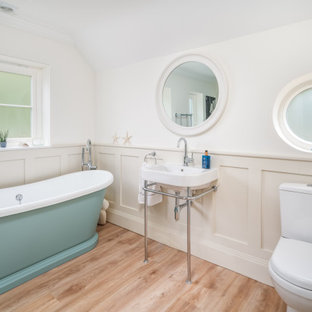 Traditional bathroom in Buckinghamshire with a one-piece toilet, white walls, light hardwood flooring, a console sink, beige floors, a single sink and wainscoting.